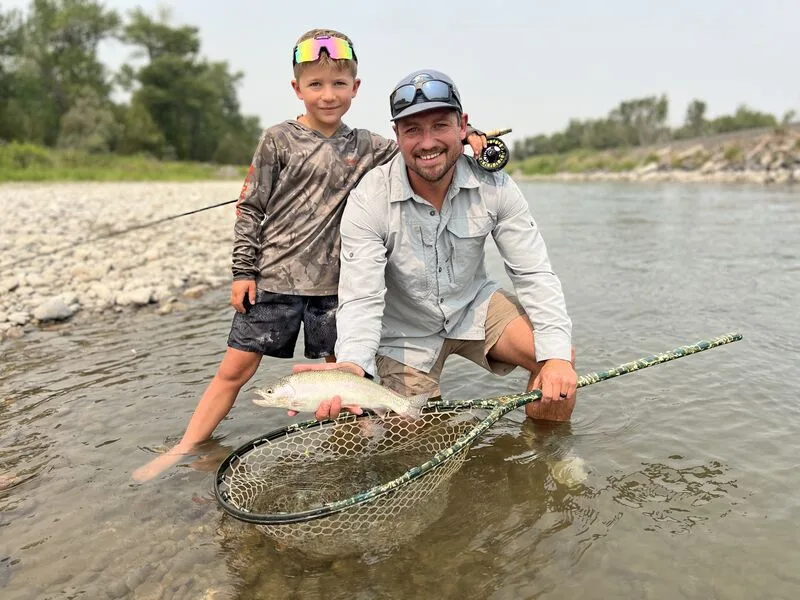 Father and son with a rainbow trout on the river