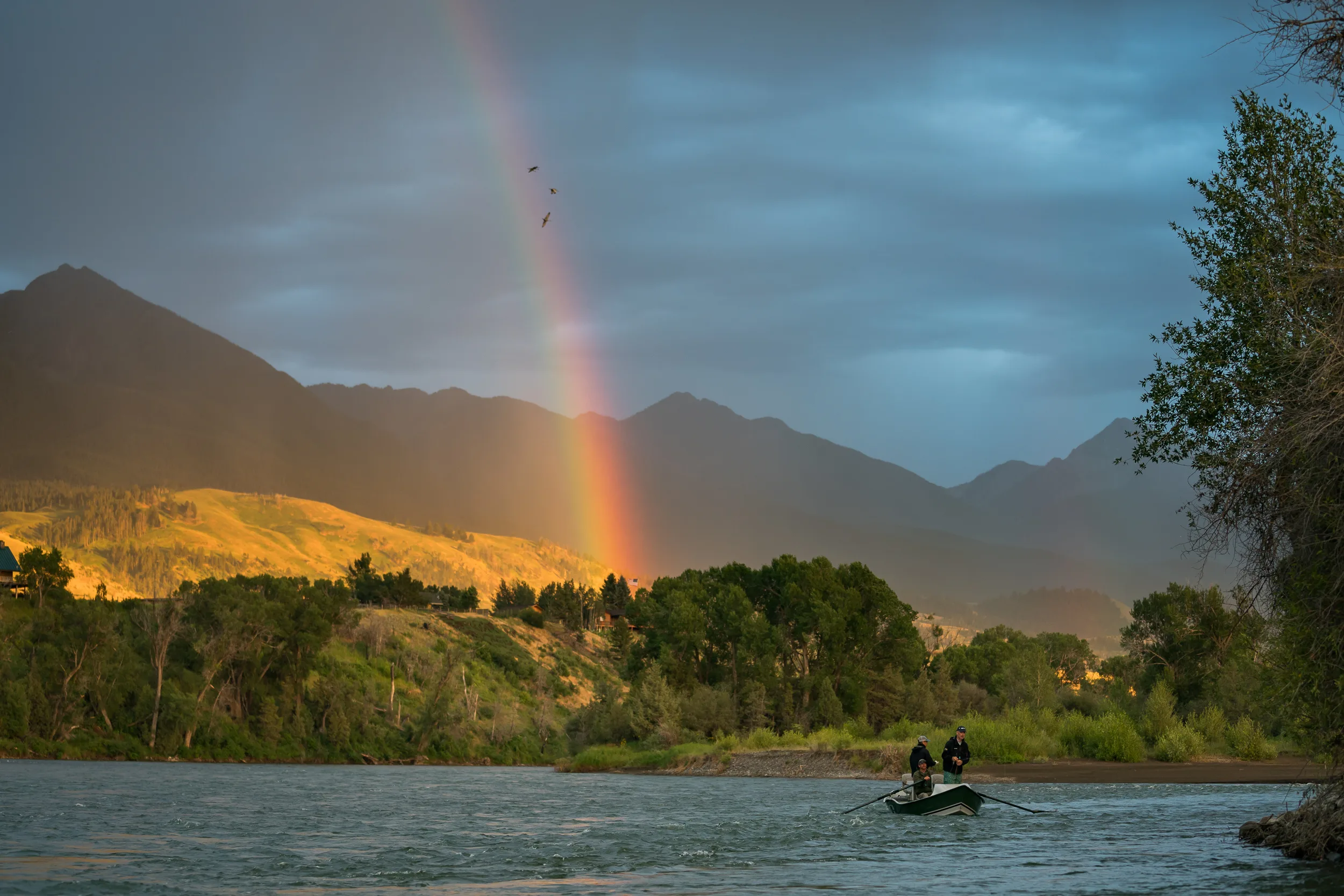 Rainbow arching over the river at sunset with golden peaks