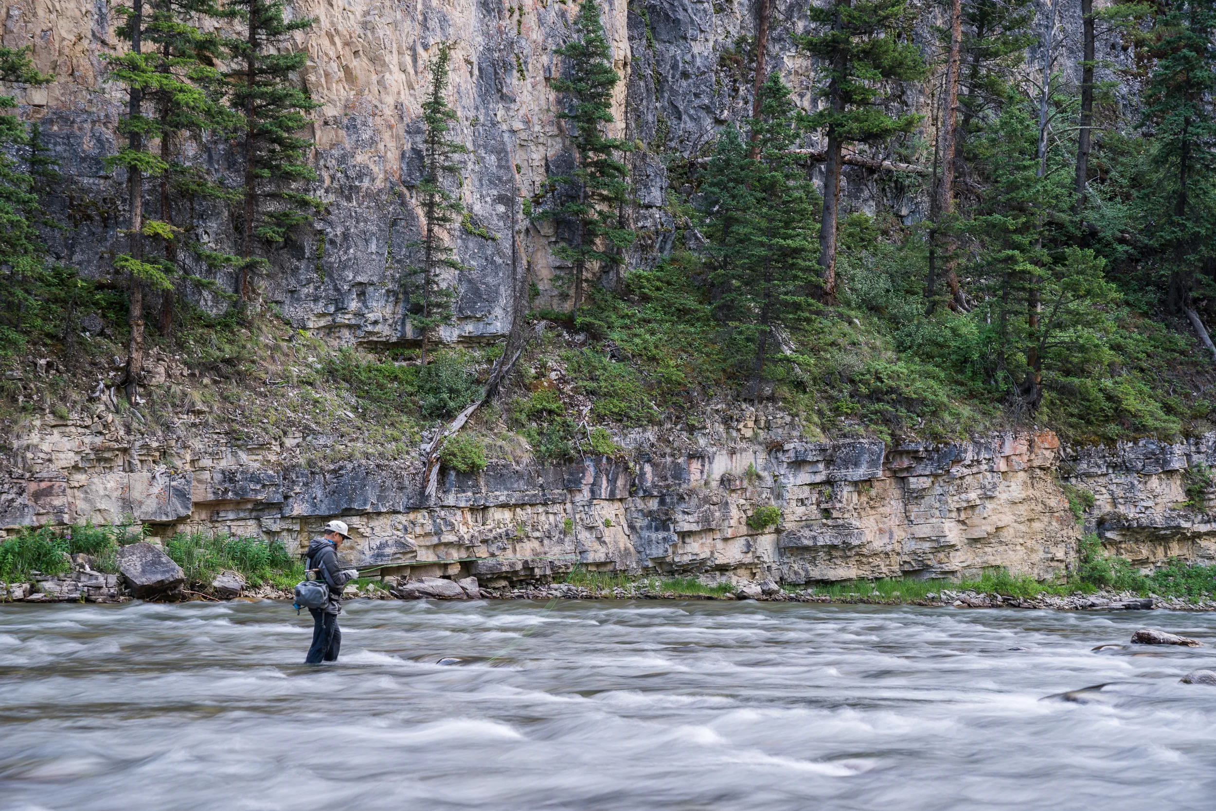 Angler wade fishing beneath canyon walls